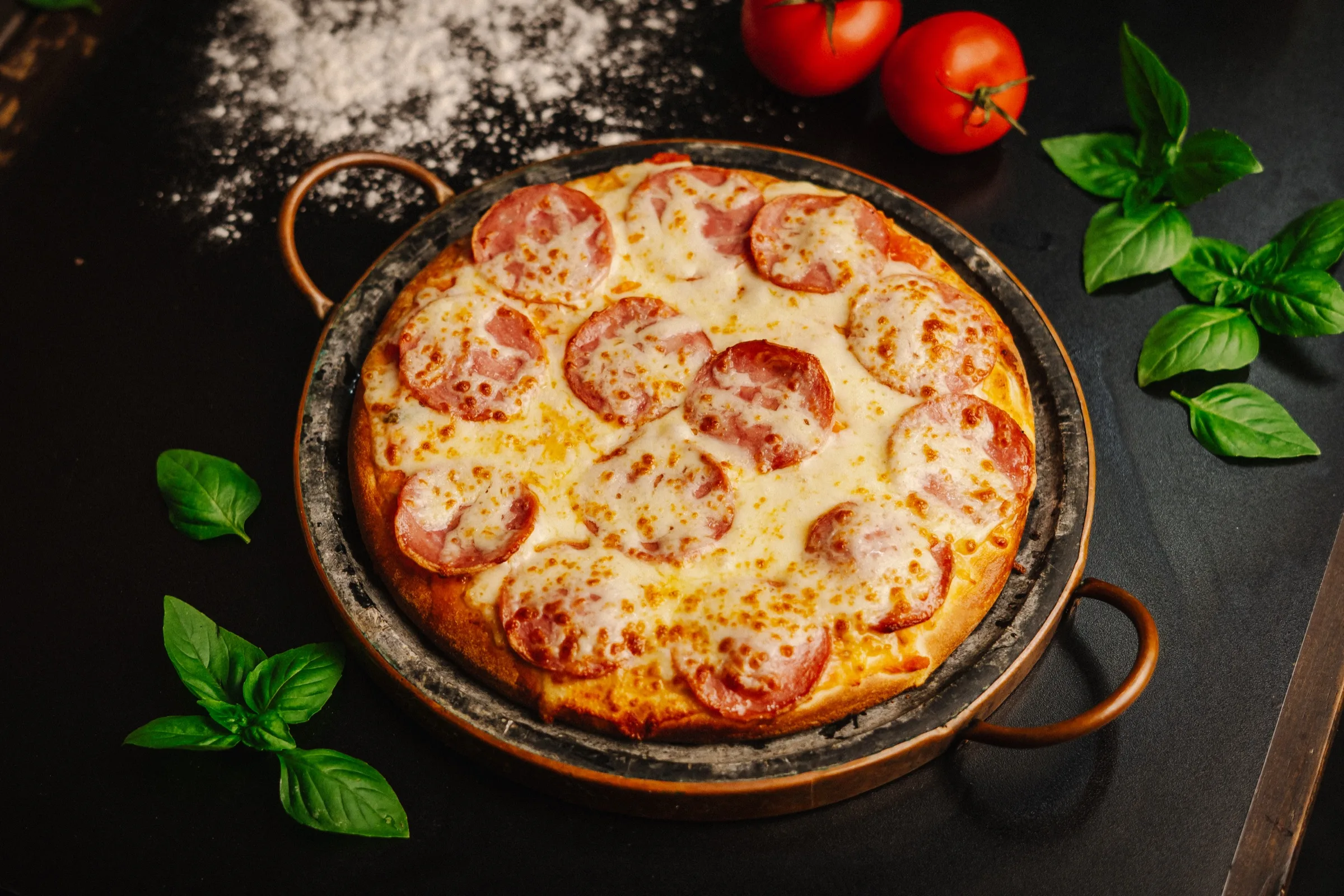 Pizza de calabresa artesanal HUGZ na forma de ferro, com tomates e manjericão