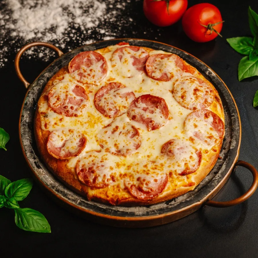 Pizza de calabresa artesanal HUGZ na forma de ferro, com tomates e manjericão